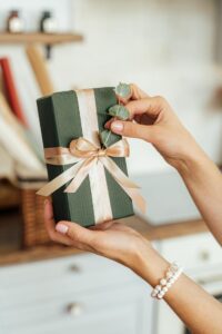 Geração Z redefinindo o conceito de beleza. Pessoa segurando uma embalagem de um produto com laço bem feito e uma flor para decorar.